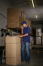 Pacific Islander warehouse worker talking on cell phone