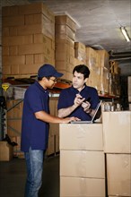 Warehouse workers using laptop and cell phone