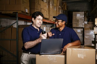 Warehouse workers using laptop and cell phone