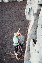 Woman and man looking up at rock climbing wall