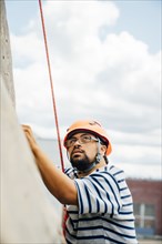 Mixed Race man climbing rock climbing wall