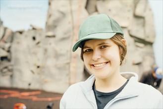 Caucasian woman smiling near rock climbing wall