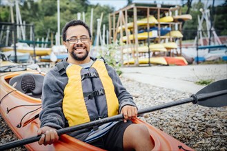 Mixed Rave man sitting in kayak holding paddle