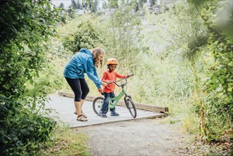 Mother helping son ride bicycle