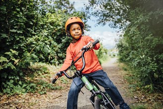 Black boy riding bicycle with helmet
