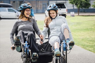 Caucasian mother and daughter riding tandem bicycle