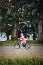 Mixed Race girl riding bicycle with training wheels