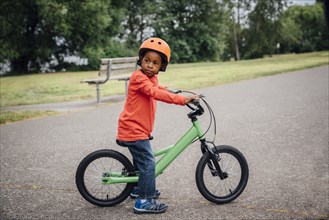 Black boy wearing helmet sitting on bicycle