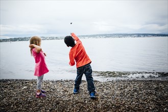 Boy and girl throwing rocks into river