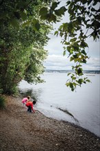 Boy and girl crouching at river