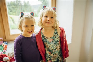 Smiling Caucasian sisters wearing cat ears