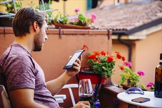 Caucasian man reading digital tablet drinking red wine
