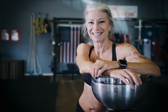 Smiling Caucasian woman leaning on bowl in gymnasium