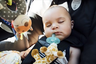 Mixed Race baby boy with pacifier sleeping in car seat