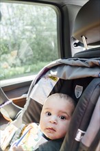 Portrait of curious Mixed Race baby boy in car seat
