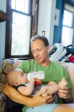 Father holding baby son drinking milk from bottle