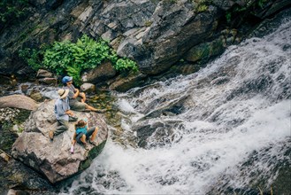 Caucasian people sitting on rock watching river rapids