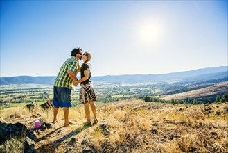 Caucasian couple standing on hill and kissing