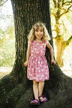 Portrait of smiling Caucasian girl leaning on tree