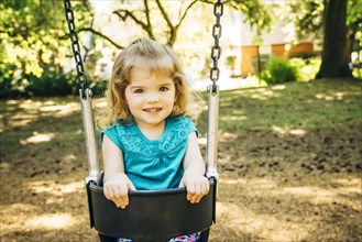 Caucasian preschool girl sitting in swing