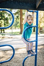 Caucasian girl climbing on playground structure