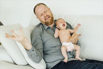 Portrait of crying father holding crying baby daughter