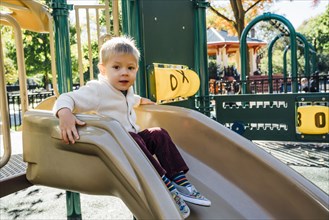 Portrait of Mixed Race boy sitting on playground slide