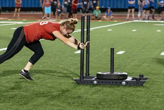 Caucasian woman pushing weight on sports field