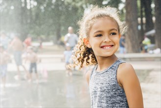 Mixed Race girl smiling in park near fountain