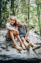 Portrait of smiling Mixed Race girls sitting on rock