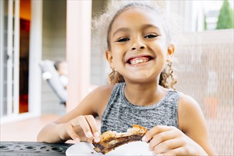 Smiling Mixed Race girl eating rib outdoors