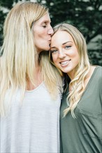 Smiling Caucasian mother kissing forehead of daughter