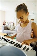 Mixed Race girl playing music on keyboard