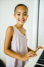 Smiling Mixed Race girl playing music on keyboard