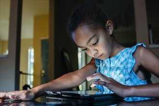 Mixed Race girl using digital tablet on table at night