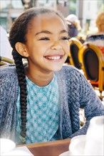 Smiling Mixed Race girl sitting at restaurant table