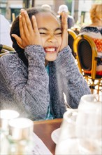 Smiling Mixed Race girl making a face at restaurant table