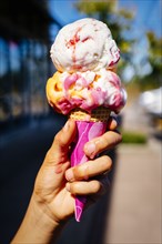 Hand of Mixed Race girl holding melting ice cream cone