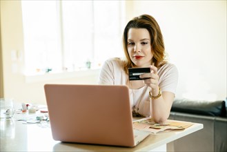 Woman sitting at counter online shopping with laptop