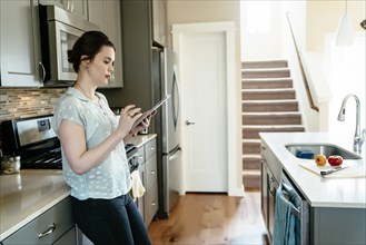 Woman using digital tablet in domestic kitchen
