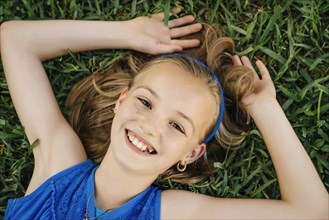 Close up portrait of smiling Caucasian girl laying on grass