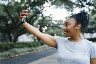 Smiling Black woman posing for cell phone selfie