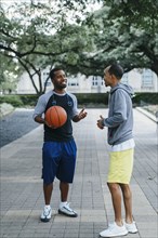 Smiling Black men holding basketball and taking