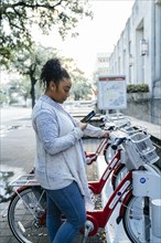 Black woman paying for bicycle rental with cell phone