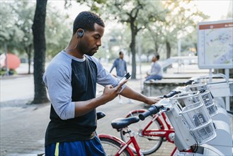 Black man paying for bicycle rental with cell phone