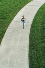 Distant mixed race woman running on path in park
