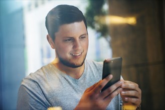 Smiling Caucasian man texting on cell phone