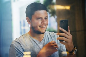 Smiling Caucasian man posing for cell phone selfie