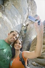 Hispanic couple taking photographs with cell phone