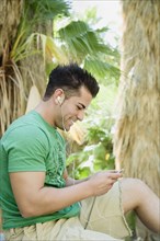 Hispanic man listening to mp3 player in tropical area